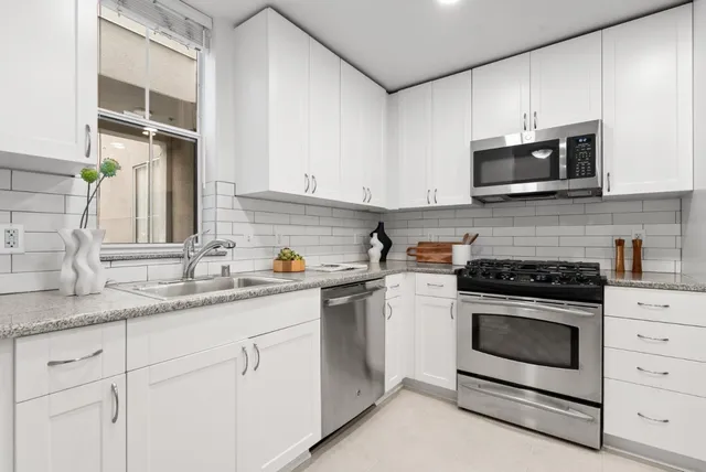 a kitchen with stainless steel appliances kitchen island granite countertop a stove a refrigerator and a microwave