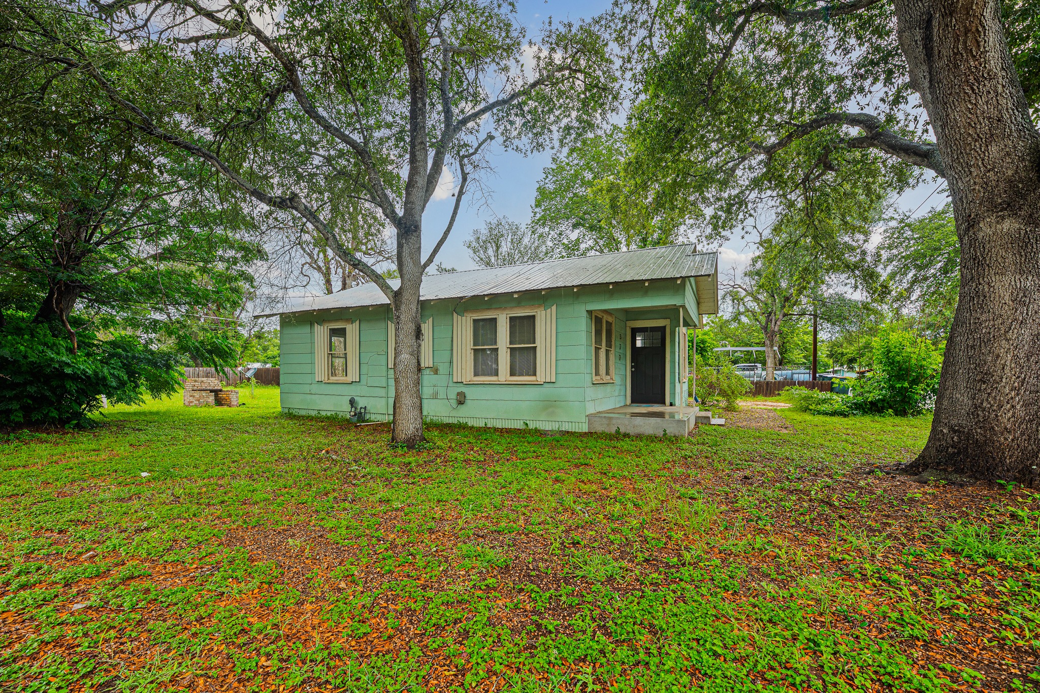322 Blanco Avenue Luling, TX 78648 - Photo 19 of 20 A charming cottage amidst verdant trees offers a tranquil living experience.