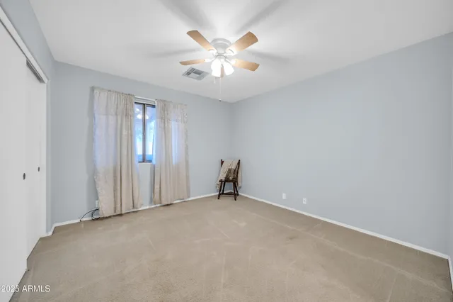 an empty room with closet and ceiling fan