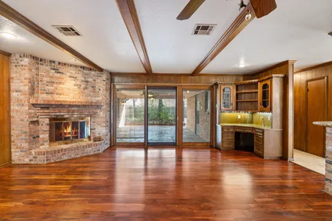 a view of a livingroom with a fireplace a ceiling fan and window