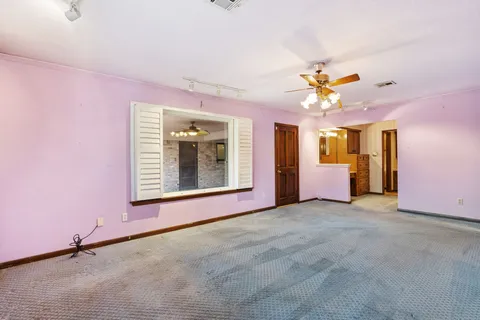 an empty room with windows and fan