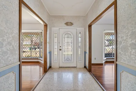 a view of a hallway with wooden floor and a livingroom with furniture