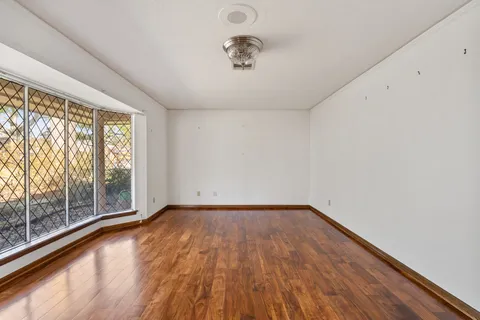 a view of an empty room with wooden floor and a window