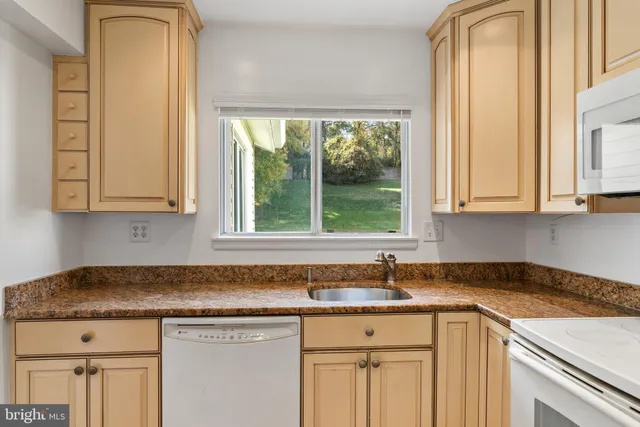 a kitchen with granite countertop white cabinets and window