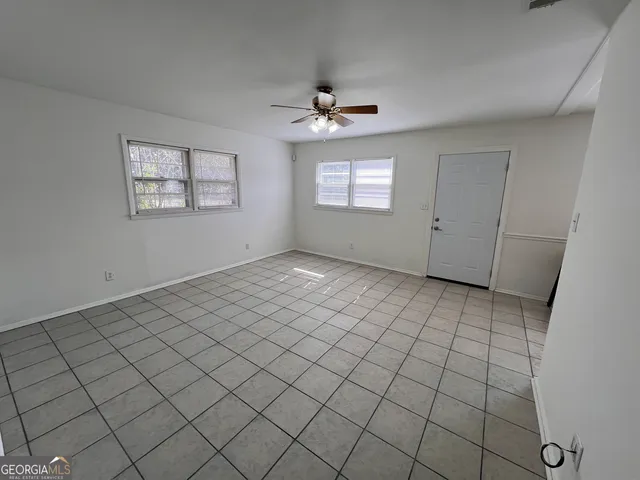 an empty room with windows and ceiling fan