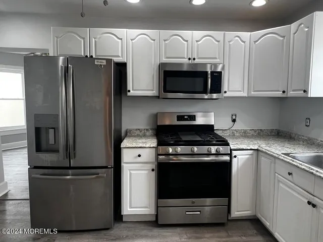 a kitchen with stainless steel appliances white cabinets white stove a microwave and a refrigerator