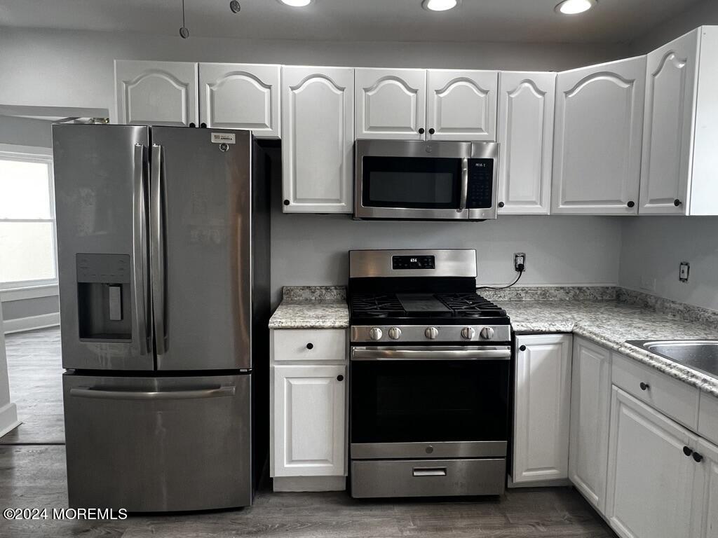 615 2nd Avenue, Unit 1 Asbury Park, NJ 07712 - Photo 21 of 39 a kitchen with stainless steel appliances white cabinets white stove a microwave and a refrigerator