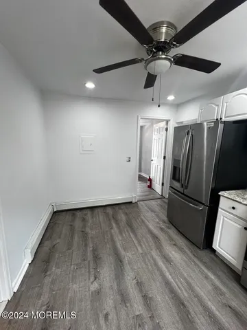 a view of a refrigerator in kitchen and an empty room