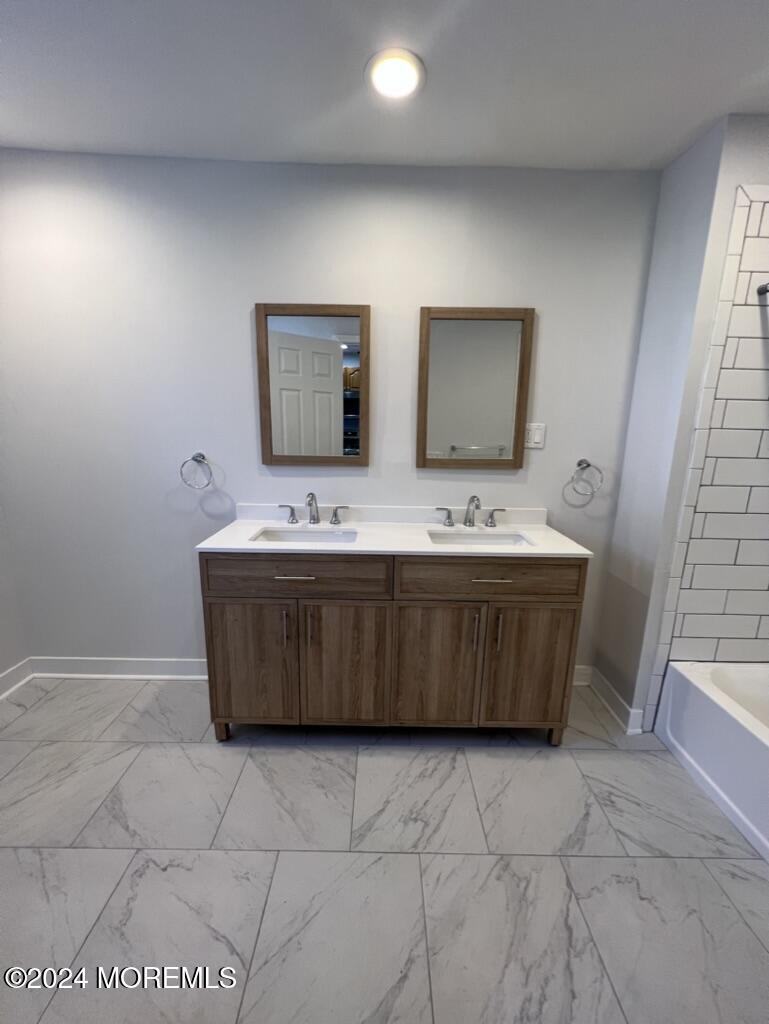 615 2nd Avenue, Unit 1 Asbury Park, NJ 07712 - Photo 25 of 39 a bathroom with a sink a mirror and vanity