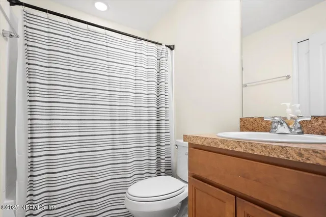 a bathroom with a granite countertop sink toilet and mirror