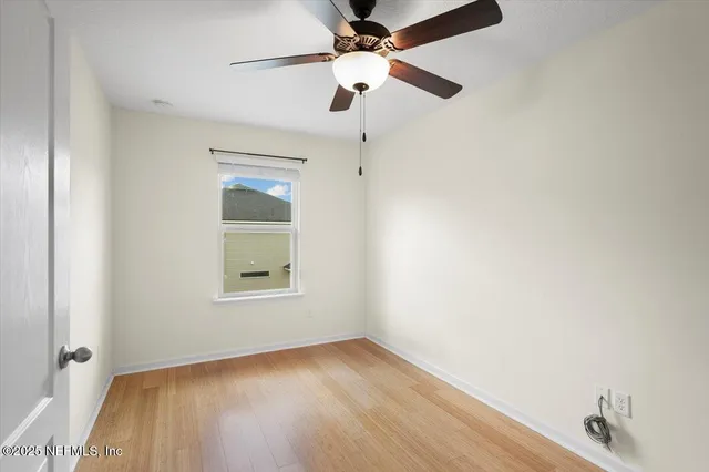 an empty room with a window and a fan