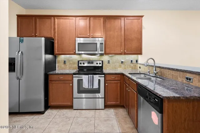 a kitchen with stainless steel appliances granite countertop a stove a sink and a refrigerator