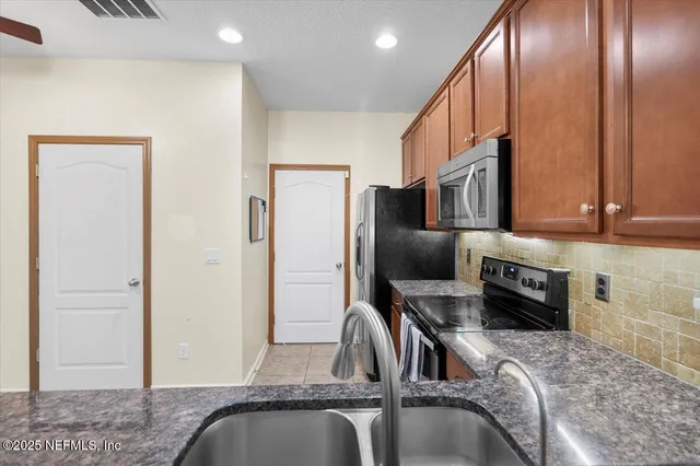 a kitchen with stainless steel appliances granite countertop a refrigerator a stove and a sink with wooden floor