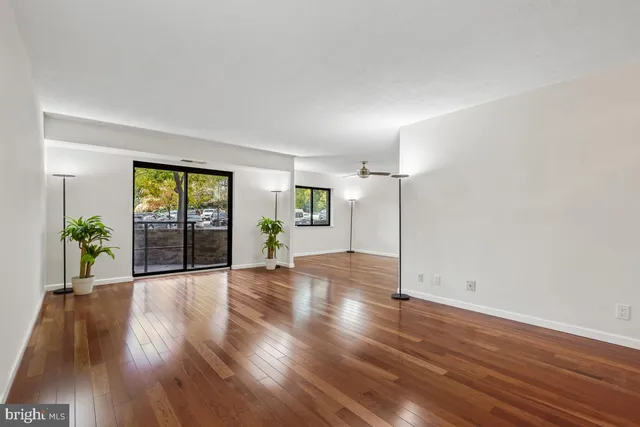 a view of empty room with wooden floor and fan