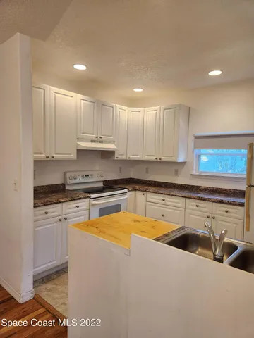 a view of a kitchen with a sink wooden cabinets and a refrigerator