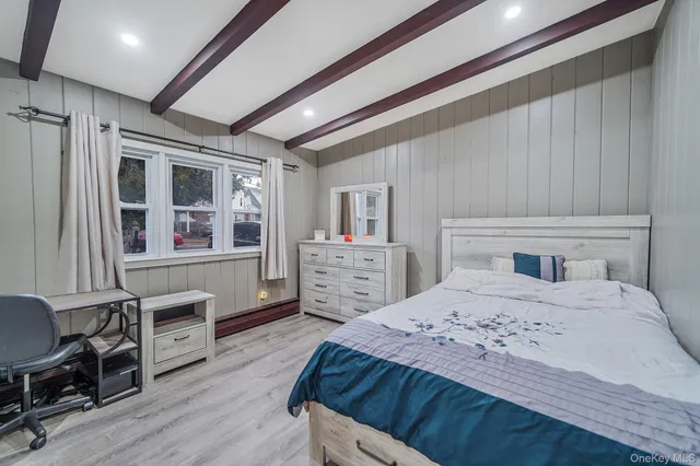 a bedroom with a bed a dresser and wooden floor