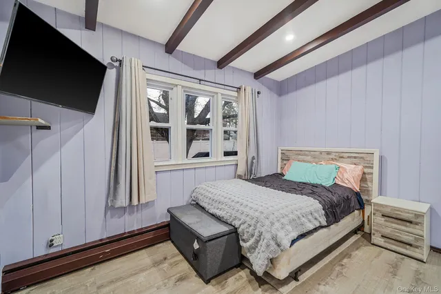 a bedroom with a bed wooden floor and flat screen tv