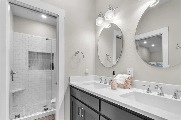a bathroom with a double vanity sink mirror and shower