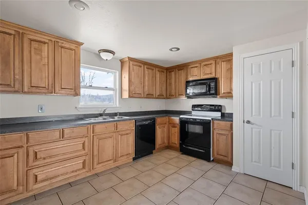 a kitchen with granite countertop white cabinets stainless steel appliances and a window