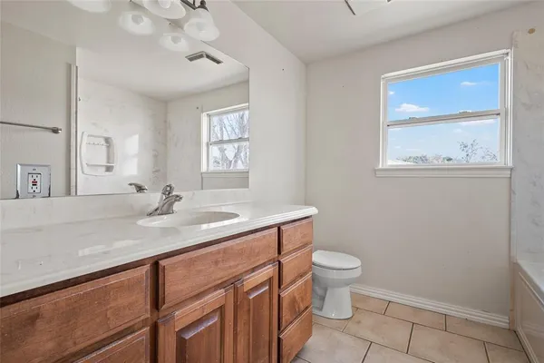 a bathroom with a granite countertop sink a toilet and a mirror