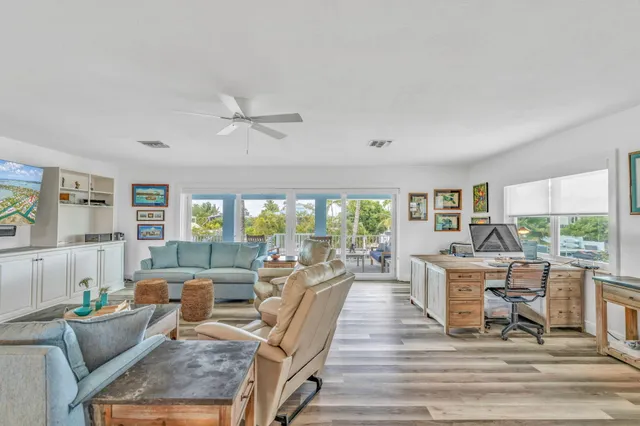 a living room with furniture a large window and wooden floor