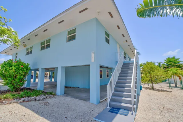 a front view of a house with wooden stairs and potted plants