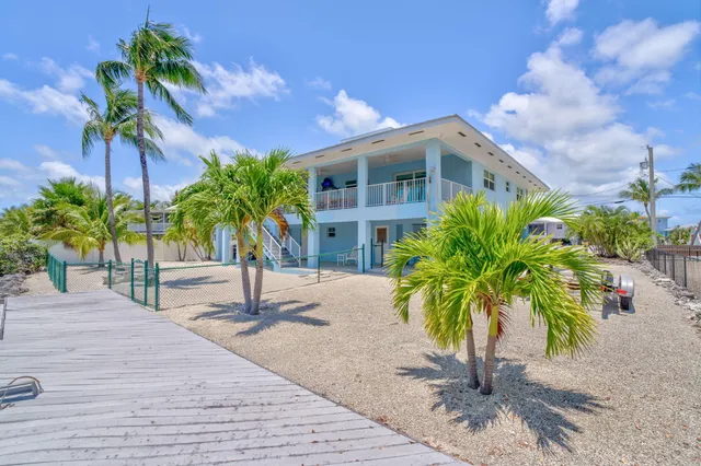 a palm tree sitting in front of a house with a yard