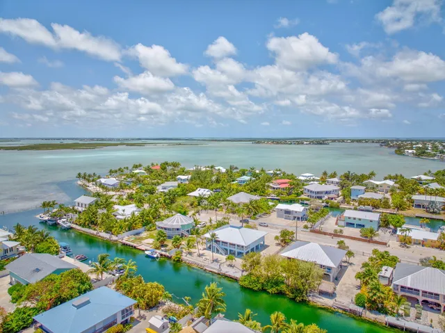 an aerial view of a city with lots of residential buildings ocean and mountain view in back