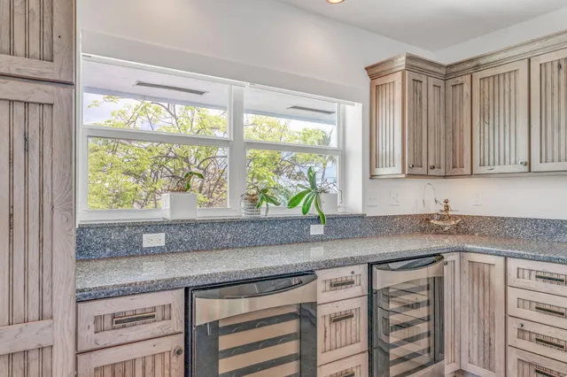 a kitchen with granite countertop a sink a window and cabinets