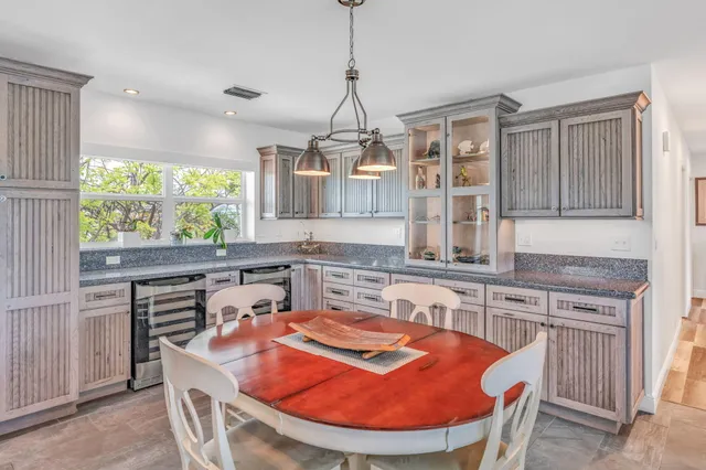 a kitchen with stainless steel appliances granite countertop a stove a sink a refrigerator white cabinets and wooden floor