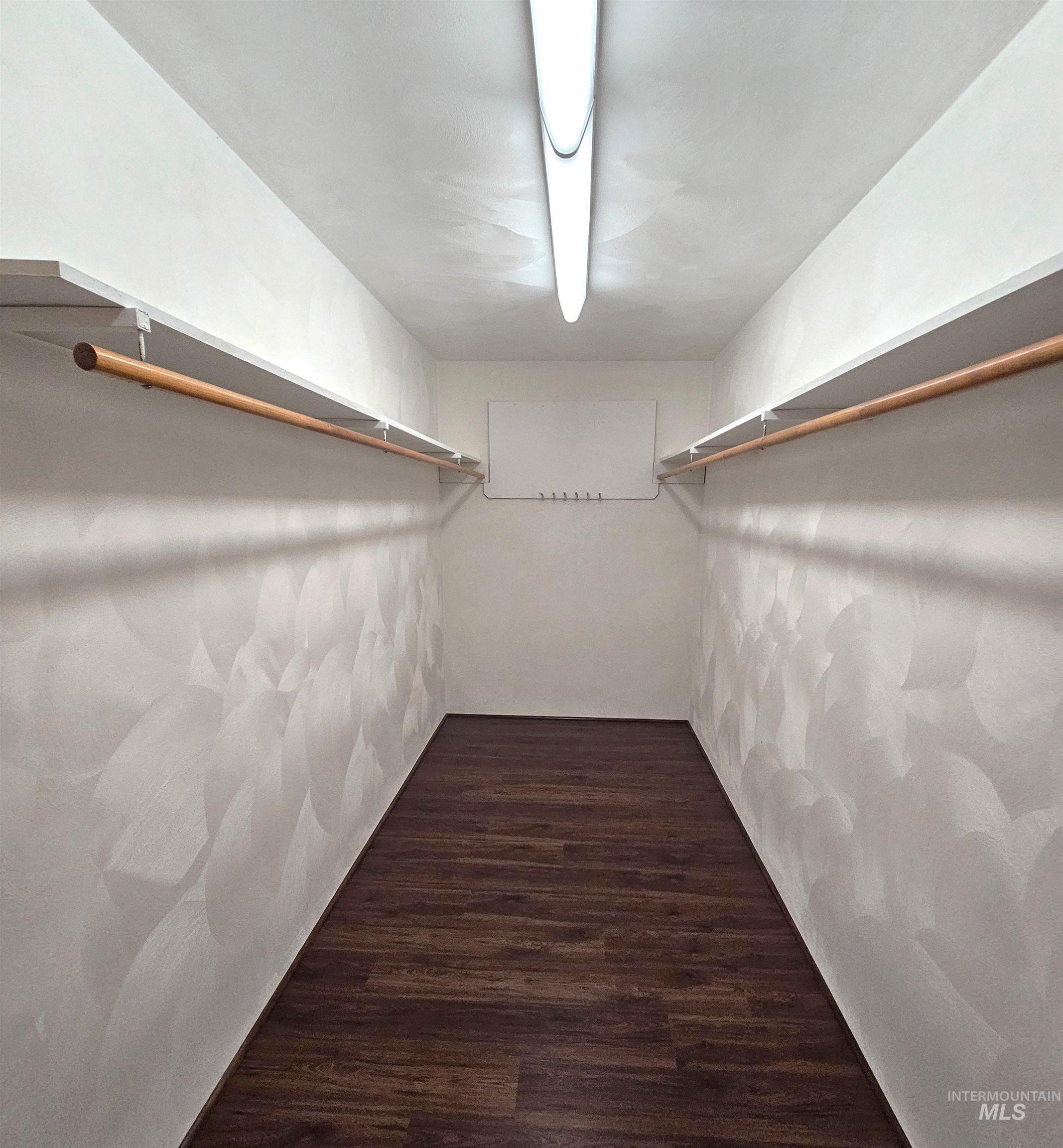 29865 Mission Creek Road Culdesac, ID 83524 - Photo 30 of 43 Walk-in closet featuring wood-finish flooring, dual shelving, dual hanging rods, and an overhead fluorescent light fixture