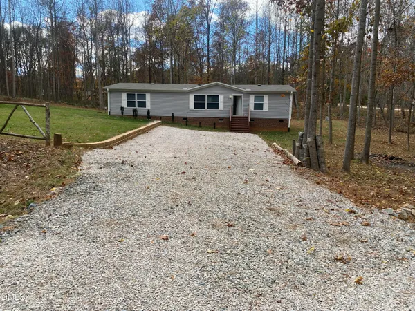 a view of house with a backyard and trees