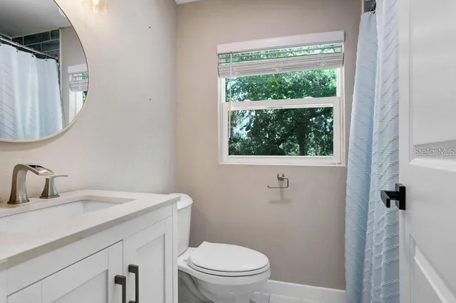 a bathroom with a toilet a sink a window and mirror