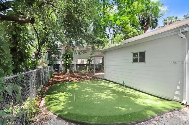 a view of a backyard with table and chairs potted plants and large tree