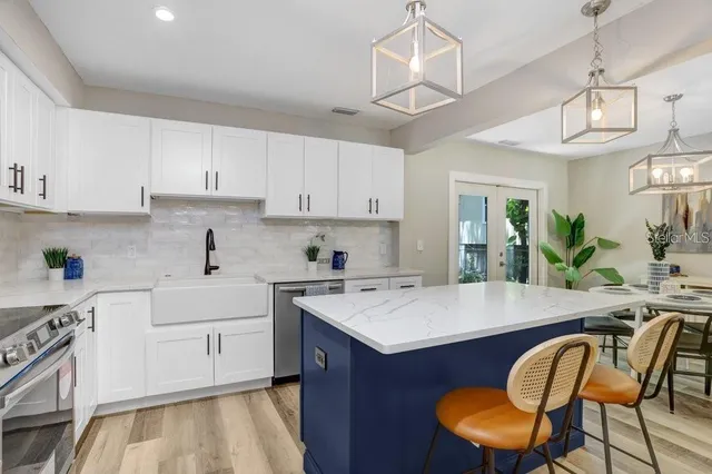 a kitchen with stainless steel appliances granite countertop a table chairs sink and cabinets