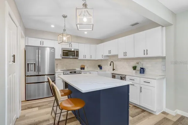 a kitchen with a refrigerator a stove a sink dishwasher and white cabinets with wooden floor