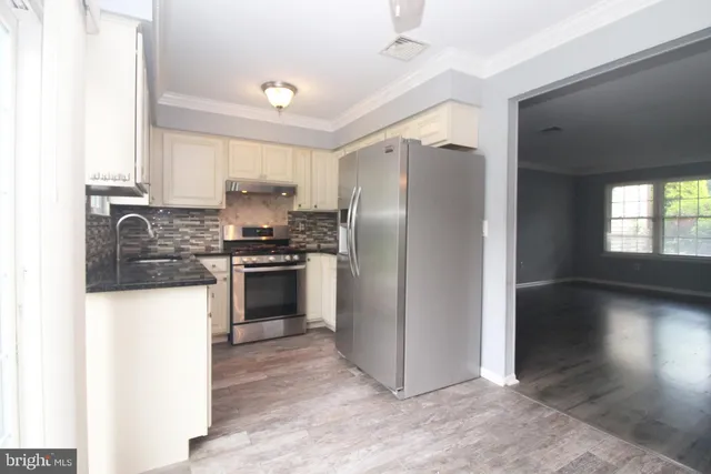 a kitchen with granite countertop a refrigerator and a stove top oven