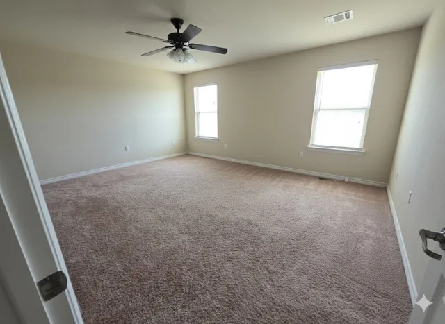 an empty room with windows and fan