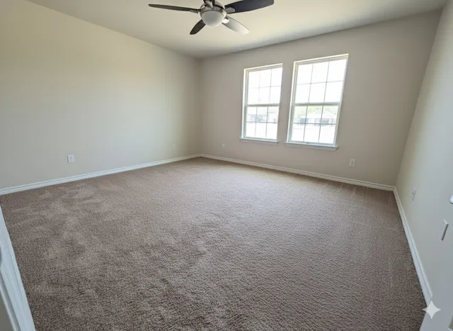 an empty room with windows and ceiling fan
