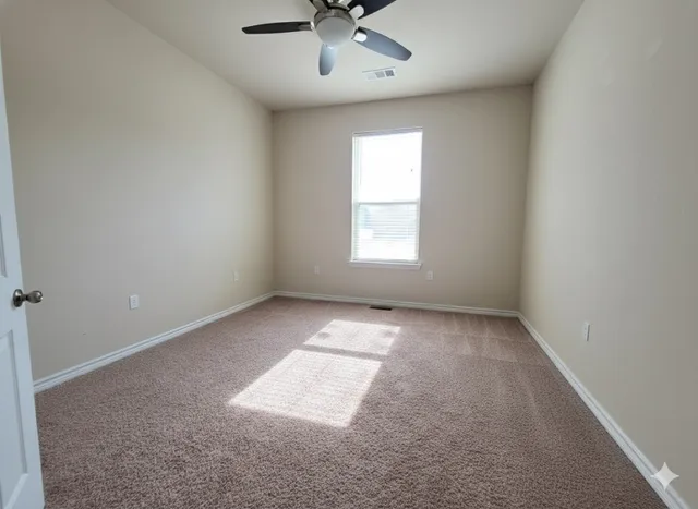an empty room with a window and a ceiling fan
