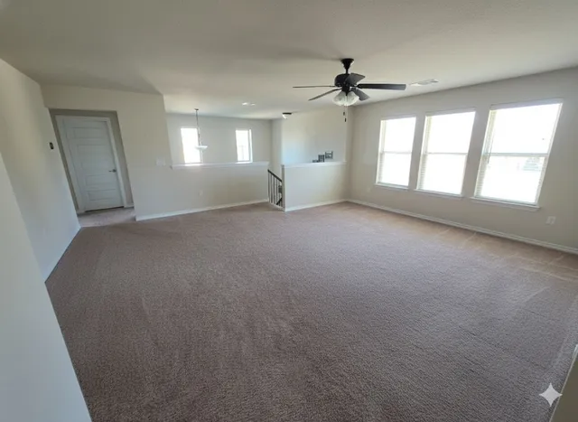 an empty room with windows and ceiling fan