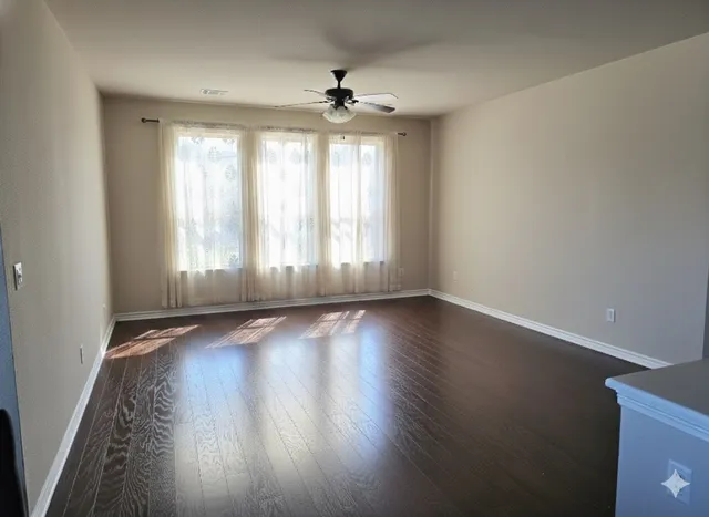 an empty room with wooden floor and windows