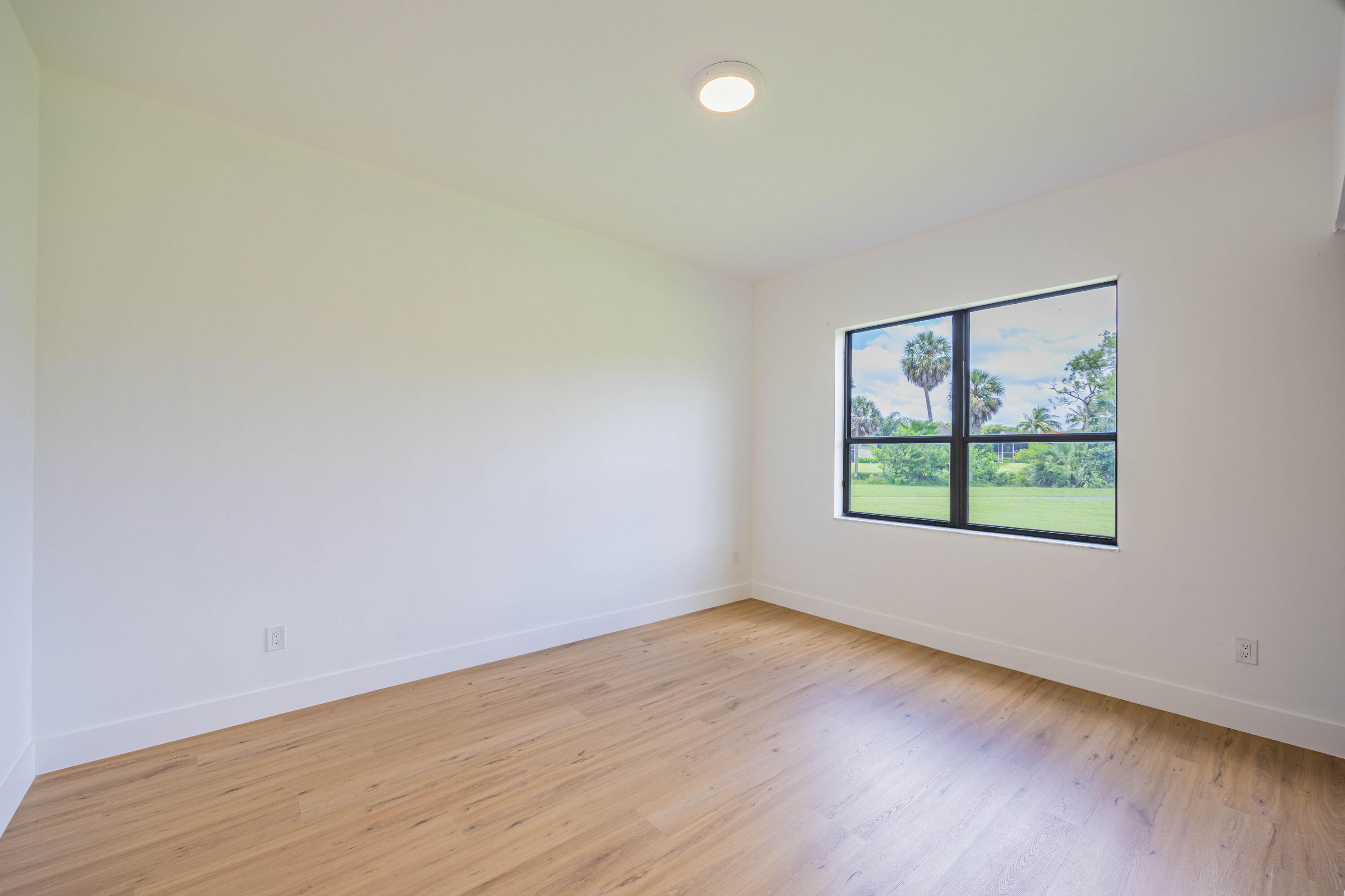 7520 La Paz Boulevard, Unit 104 Boca Raton, FL 33433 - Photo 23 of 56 an empty room with wooden floor and windows