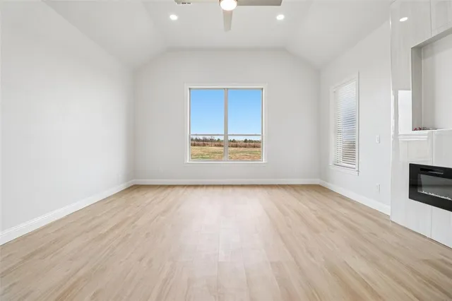 an empty room with wooden floor cabinet and windows