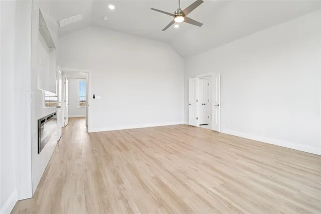 a view of empty room with wooden floor and fan