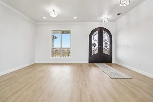 an empty room with wooden floor cabinet and windows