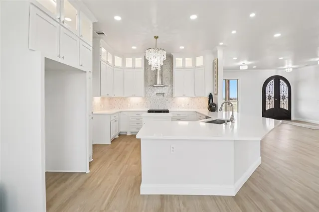a large white kitchen with a large island oven a stove and wooden floors