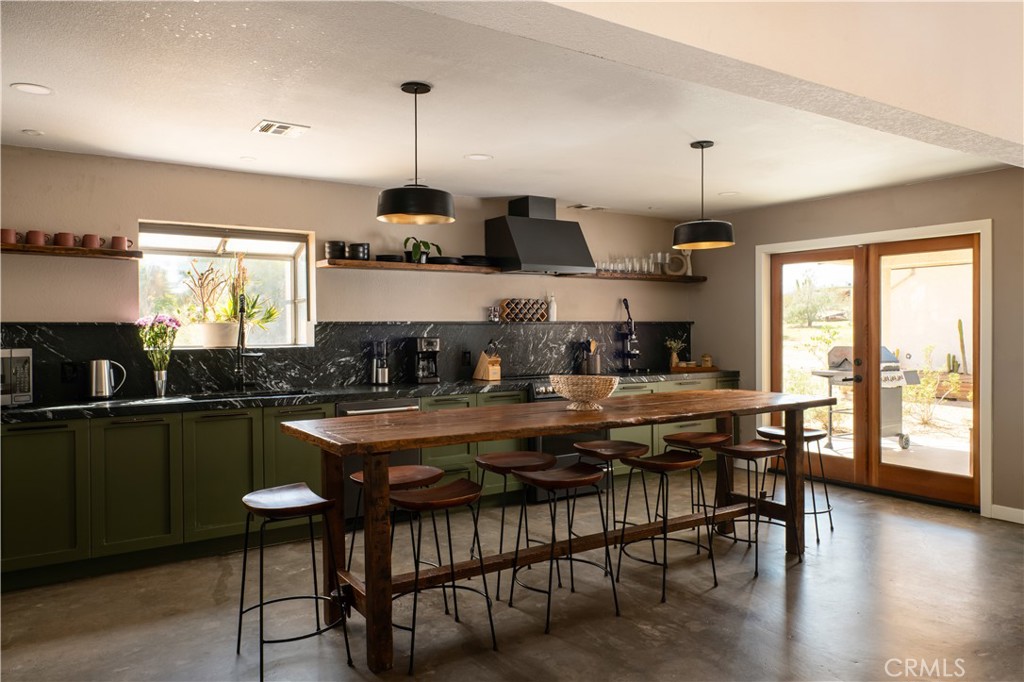 382 Cherokee Trail Yucca Valley, CA 92284 - Photo 6 of 33 a kitchen with stainless steel appliances granite countertop a stove top oven a sink a dining table and chairs with wooden floor