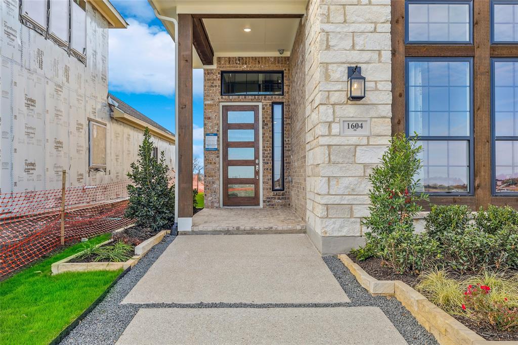 1604 Casting Ridge Mesquite, TX 75181 - Photo 4 of 38 Stone and brick exterior featuring a covered entry, wood-paneled windows, and a modern front door with frosted glass panels