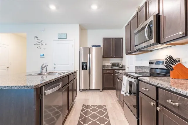 a kitchen with stainless steel appliances granite countertop a sink stove and refrigerator